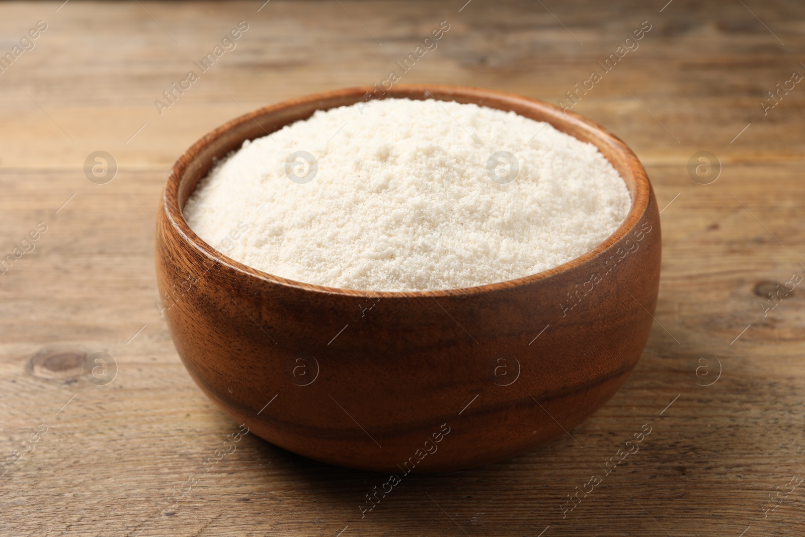 Photo of Organic coconut flour in bowl on wooden table, closeup