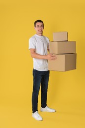 Photo of Moving into new house. Man with cardboard boxes on yellow background