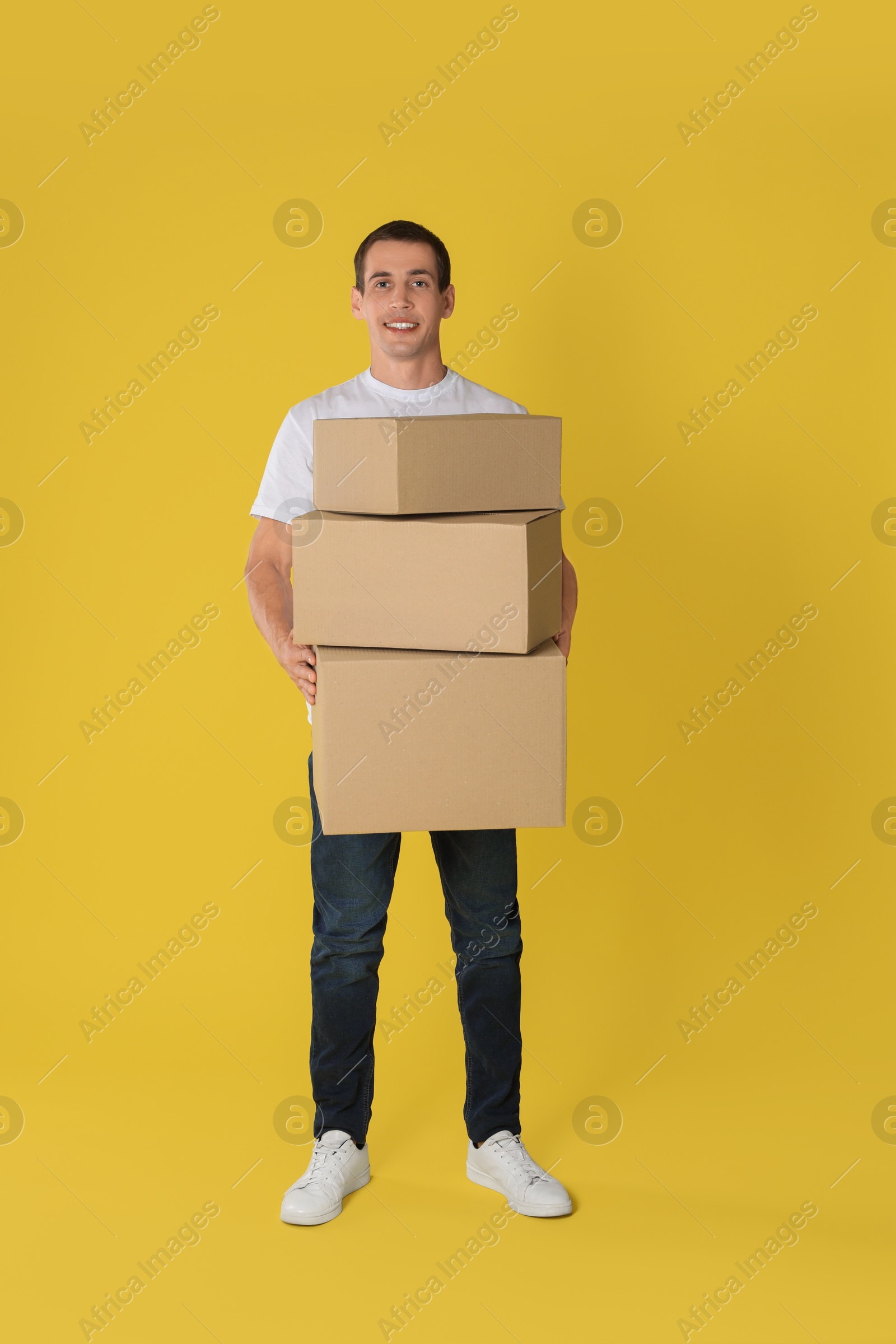 Photo of Moving into new house. Man with cardboard boxes on yellow background