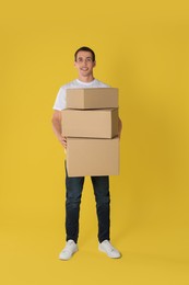 Moving into new house. Man with cardboard boxes on yellow background