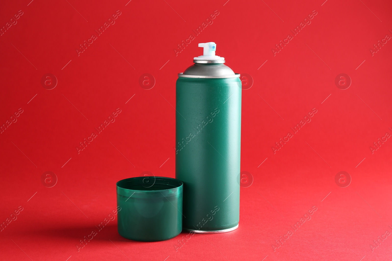 Photo of One green spray paint can on red background