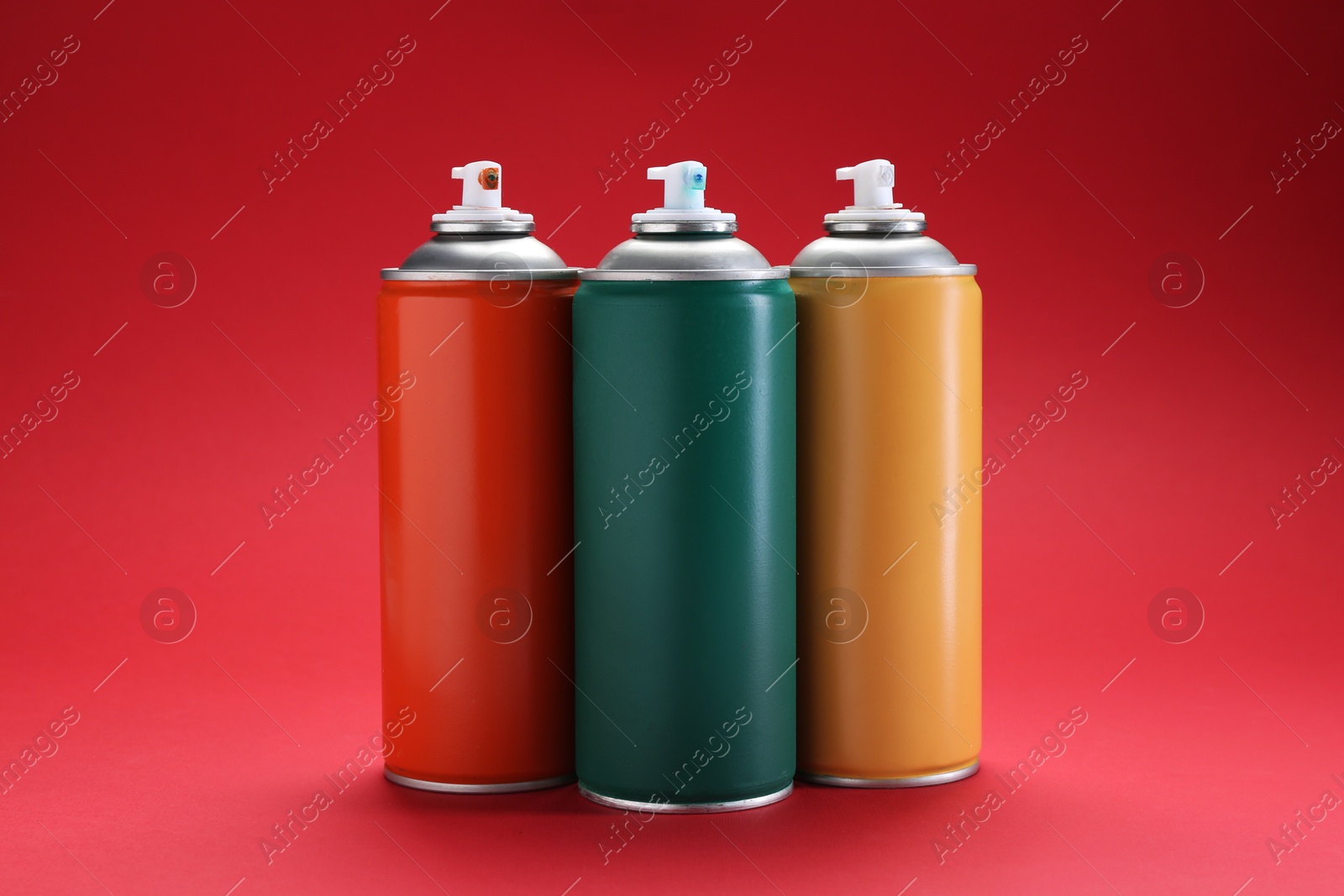 Photo of Many spray paint cans on red background