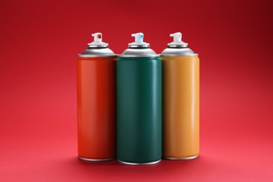 Many spray paint cans on red background