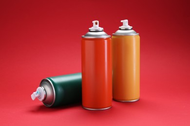 Photo of Many spray paint cans on red background