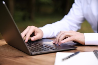 Businessman working with laptop at table outdoors, closeup. Remote job