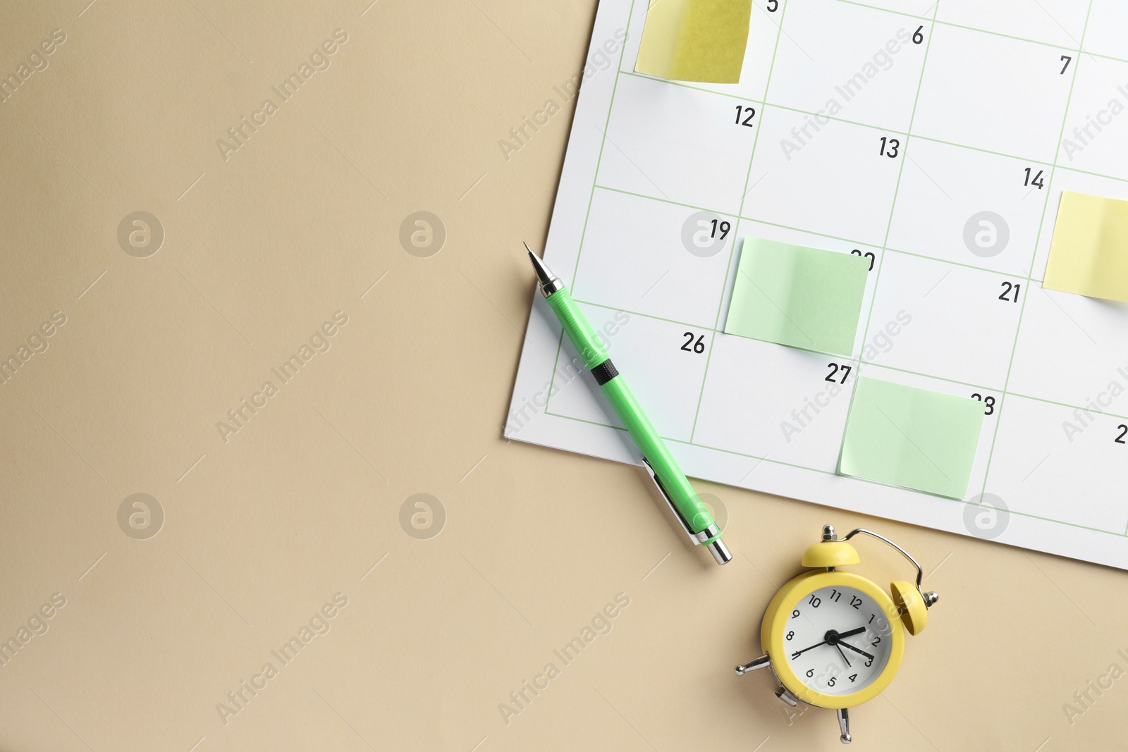 Photo of Timetable. Calendar page with sticky notes, pen and alarm clock on beige background, top view. Space for text