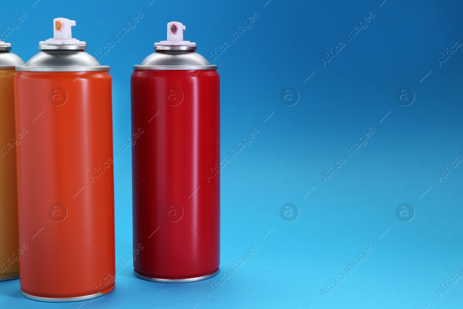 Photo of Many spray paint cans on light blue background, space for text