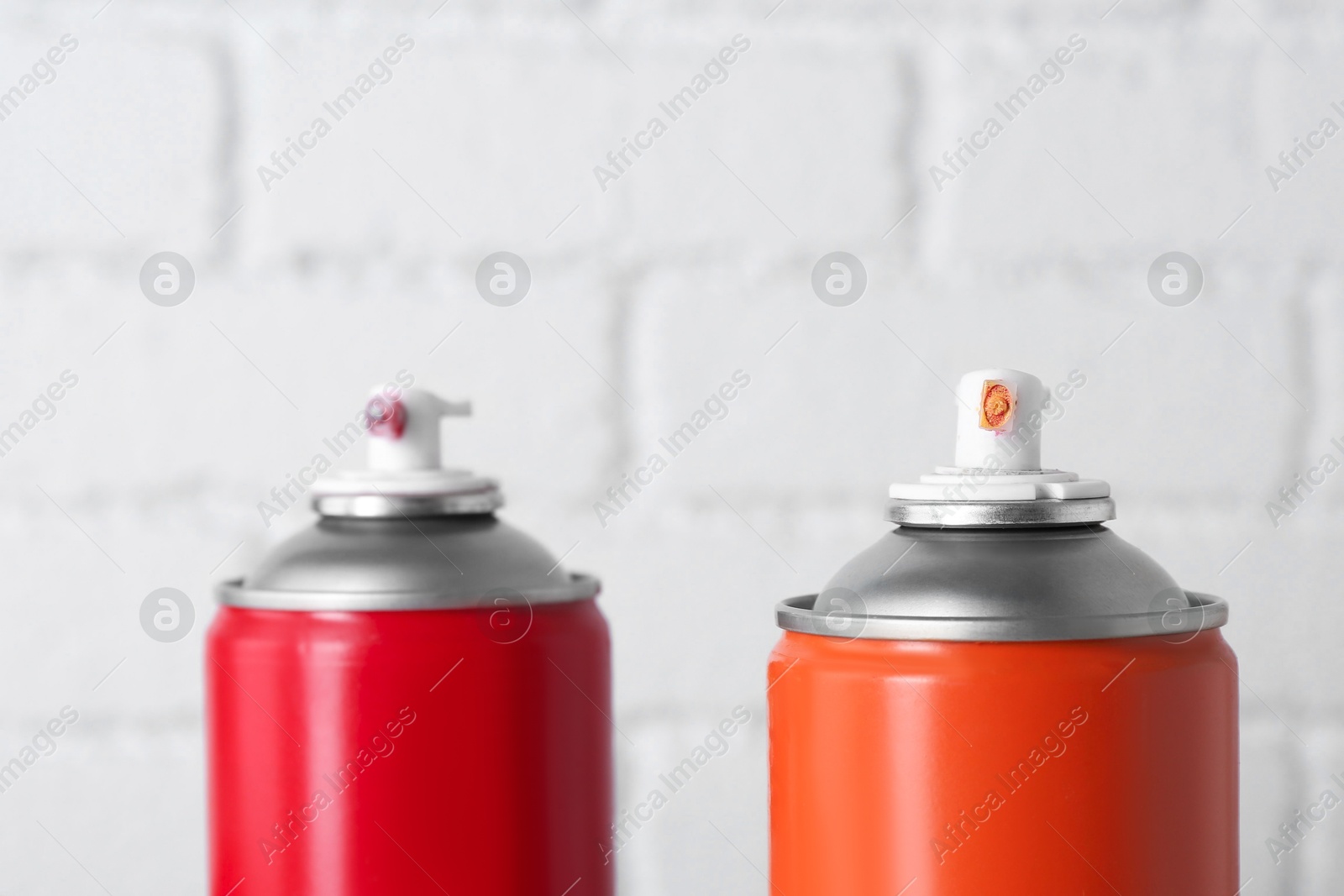 Photo of Cans of spray paint near white brick wall