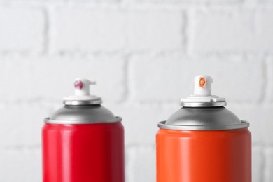 Cans of spray paint near white brick wall