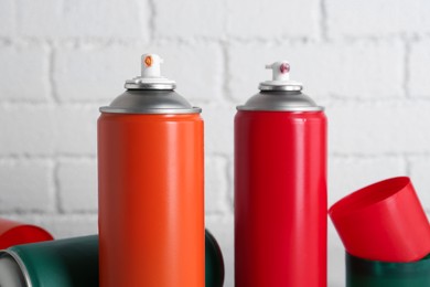 Cans of spray paint near white brick wall