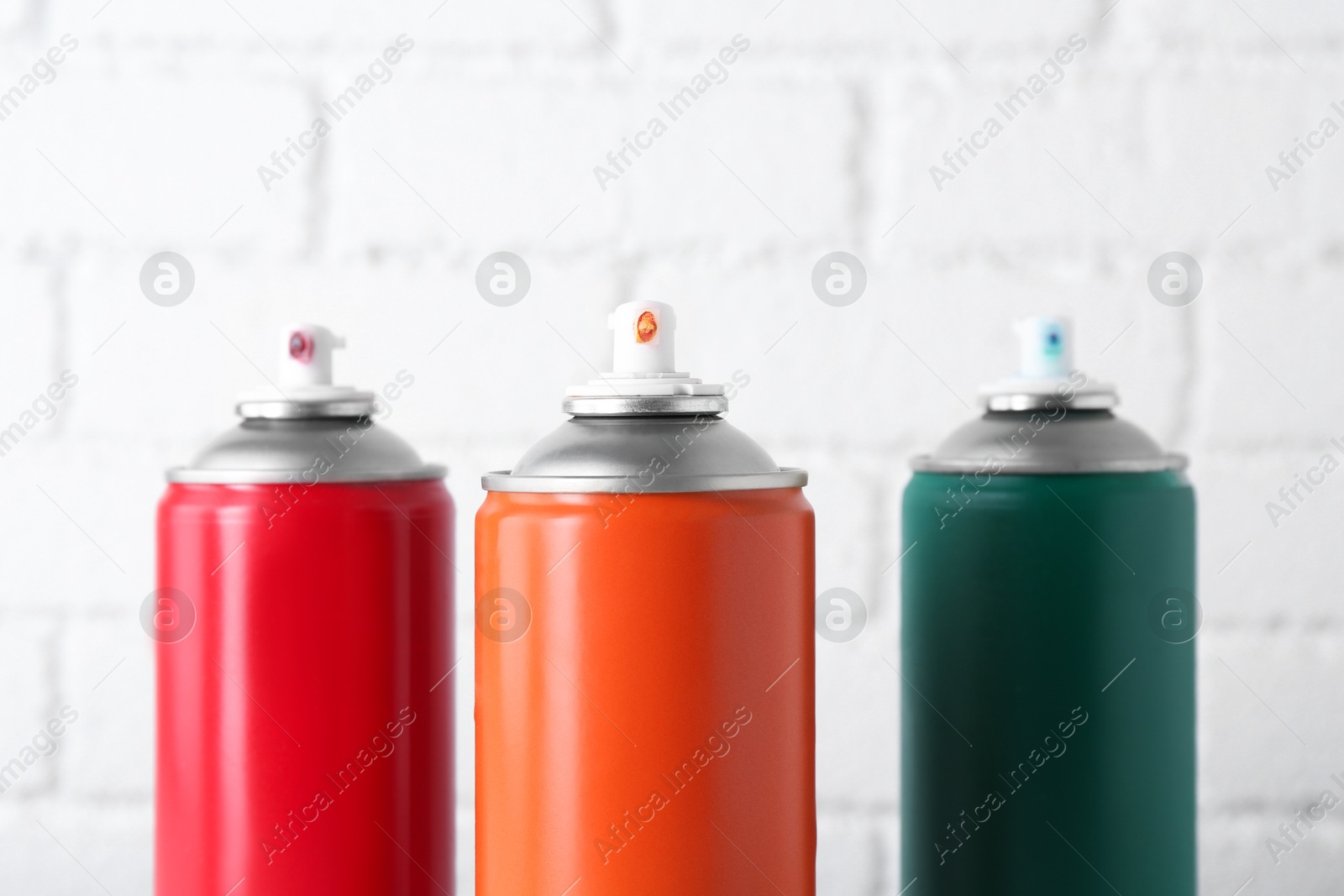 Photo of Cans of spray paint near white brick wall