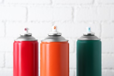 Cans of spray paint near white brick wall