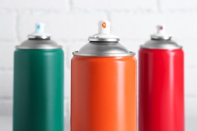 Photo of Cans of spray paint near white brick wall