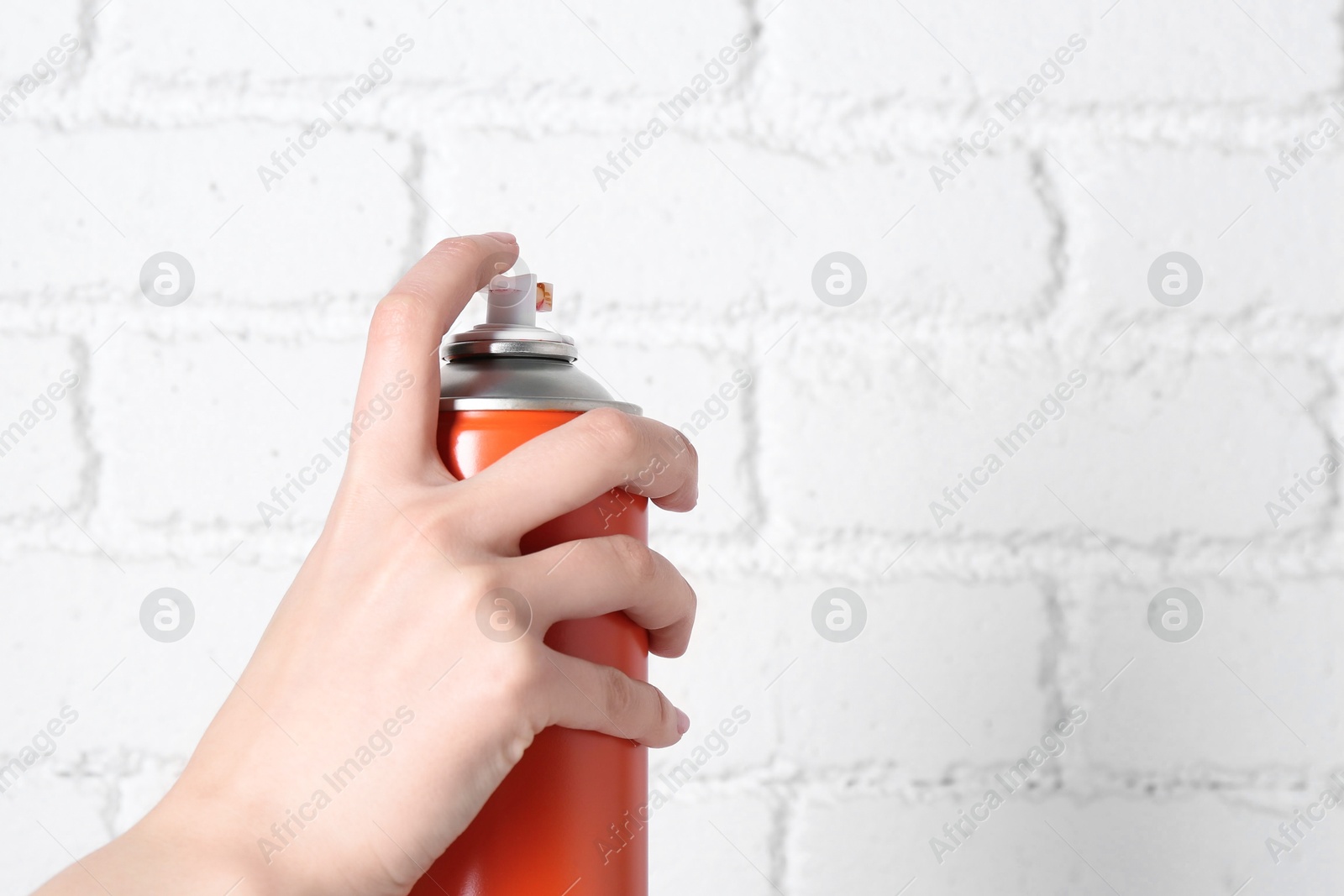 Photo of Woman with can of spray paint near white brick wall, closeup. Space for text