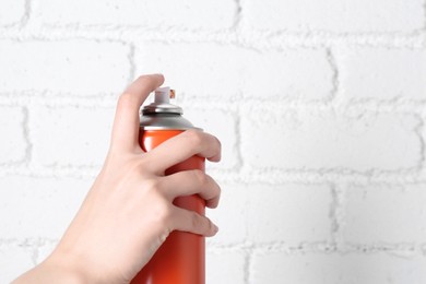 Photo of Woman with can of spray paint near white brick wall, closeup. Space for text