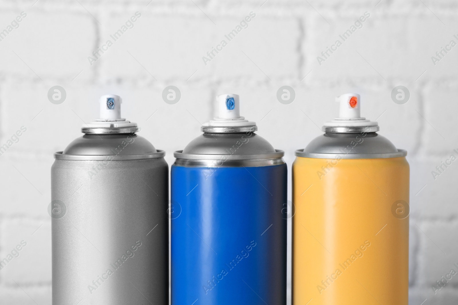 Photo of Cans of spray paint near white brick wall