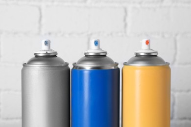 Photo of Cans of spray paint near white brick wall