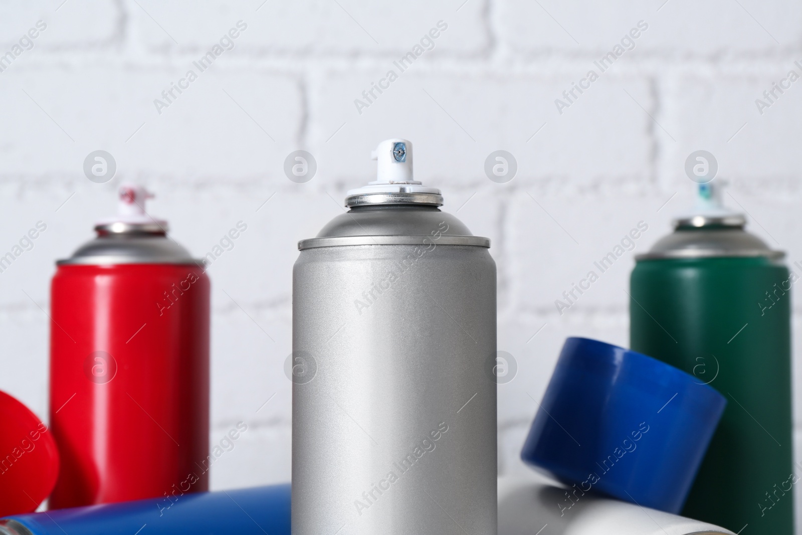 Photo of Cans of spray paint near white brick wall