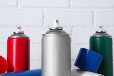 Photo of Cans of spray paint near white brick wall