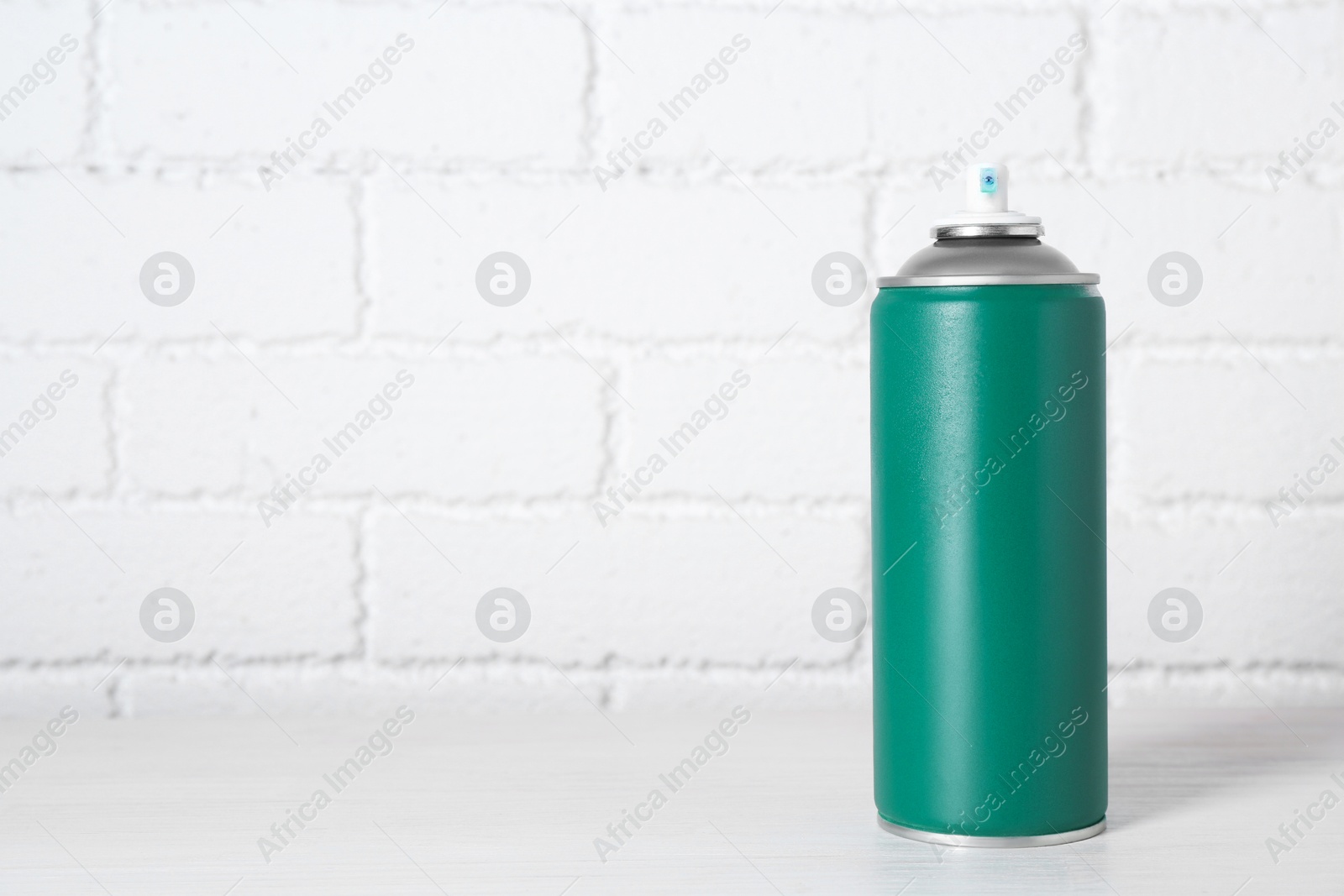 Photo of Can of spray paint on wooden table near white brick wall, space for text