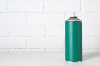 Photo of Can of spray paint on wooden table near white brick wall, space for text