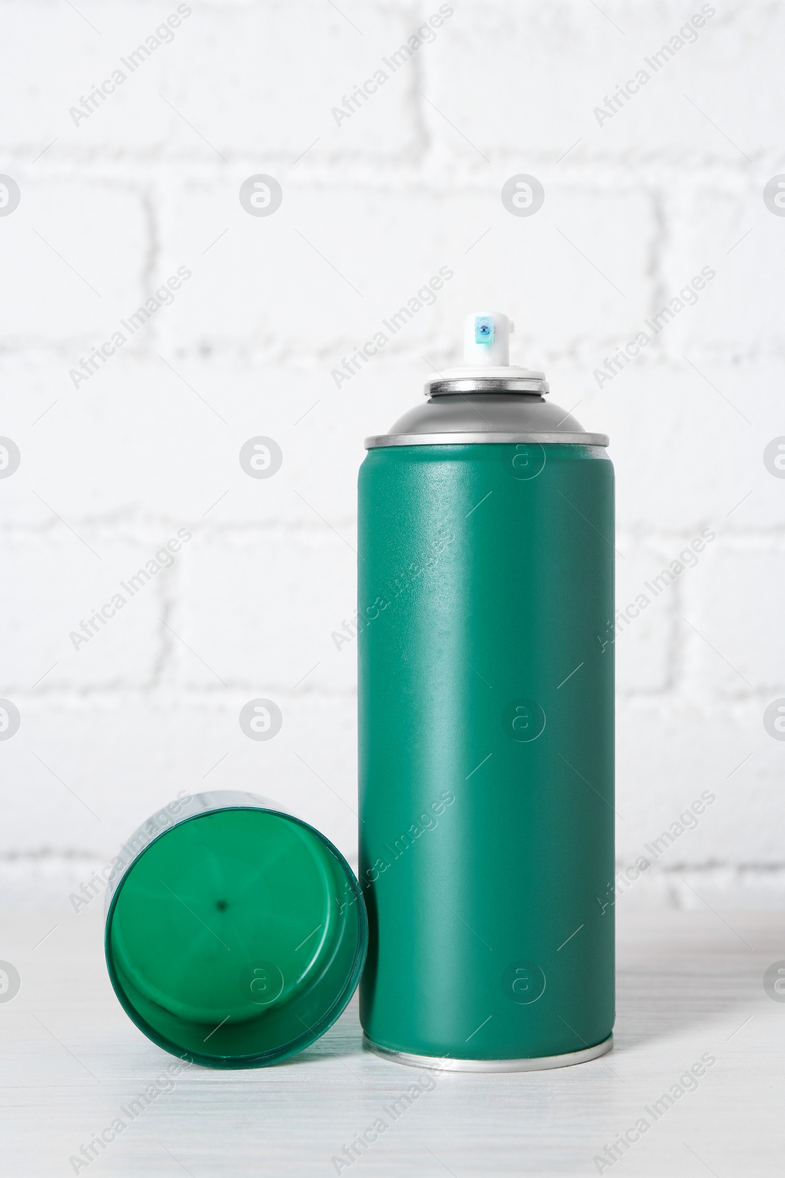 Photo of Can of spray paint on wooden table near white brick wall