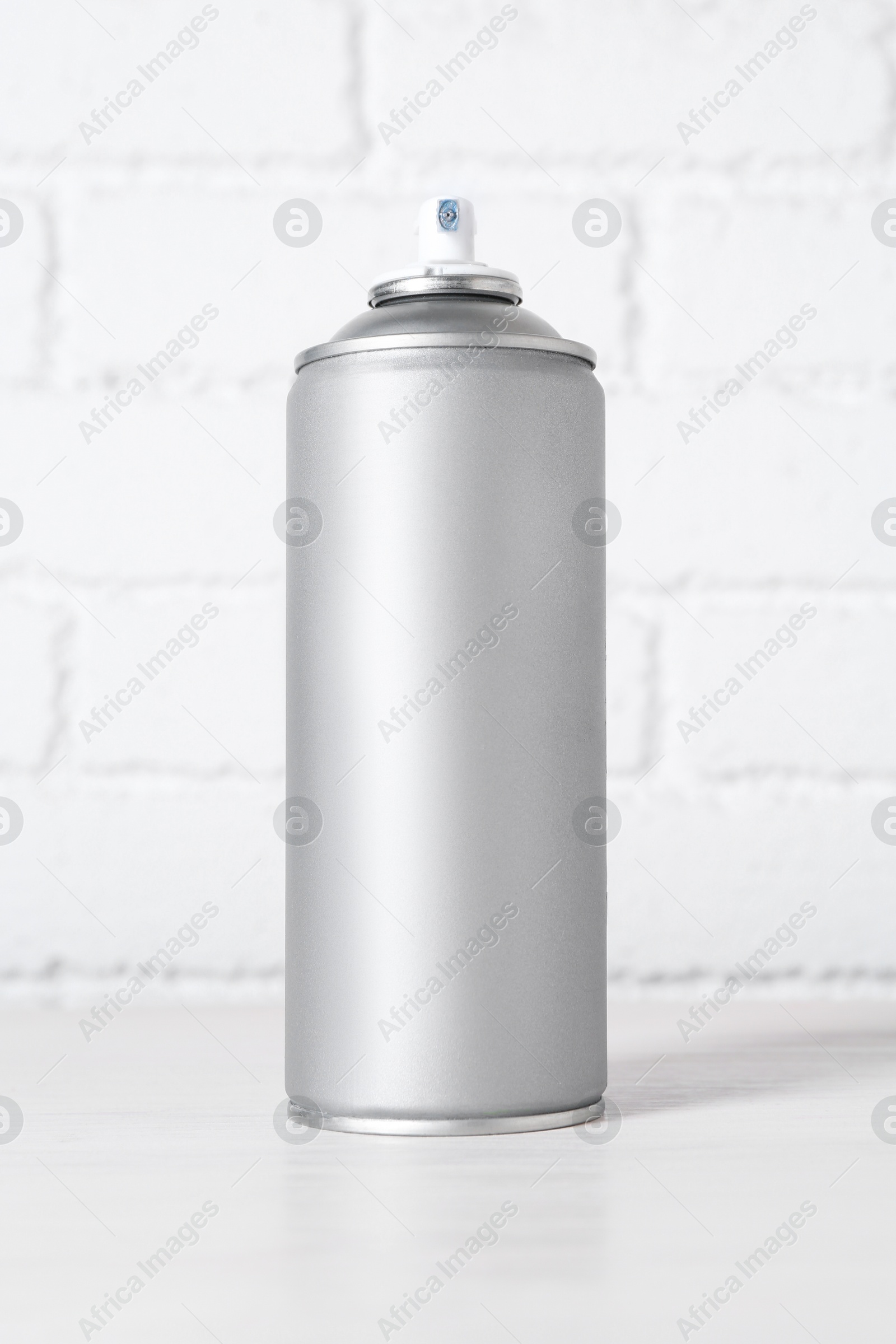 Photo of Can of spray paint on table near white brick wall