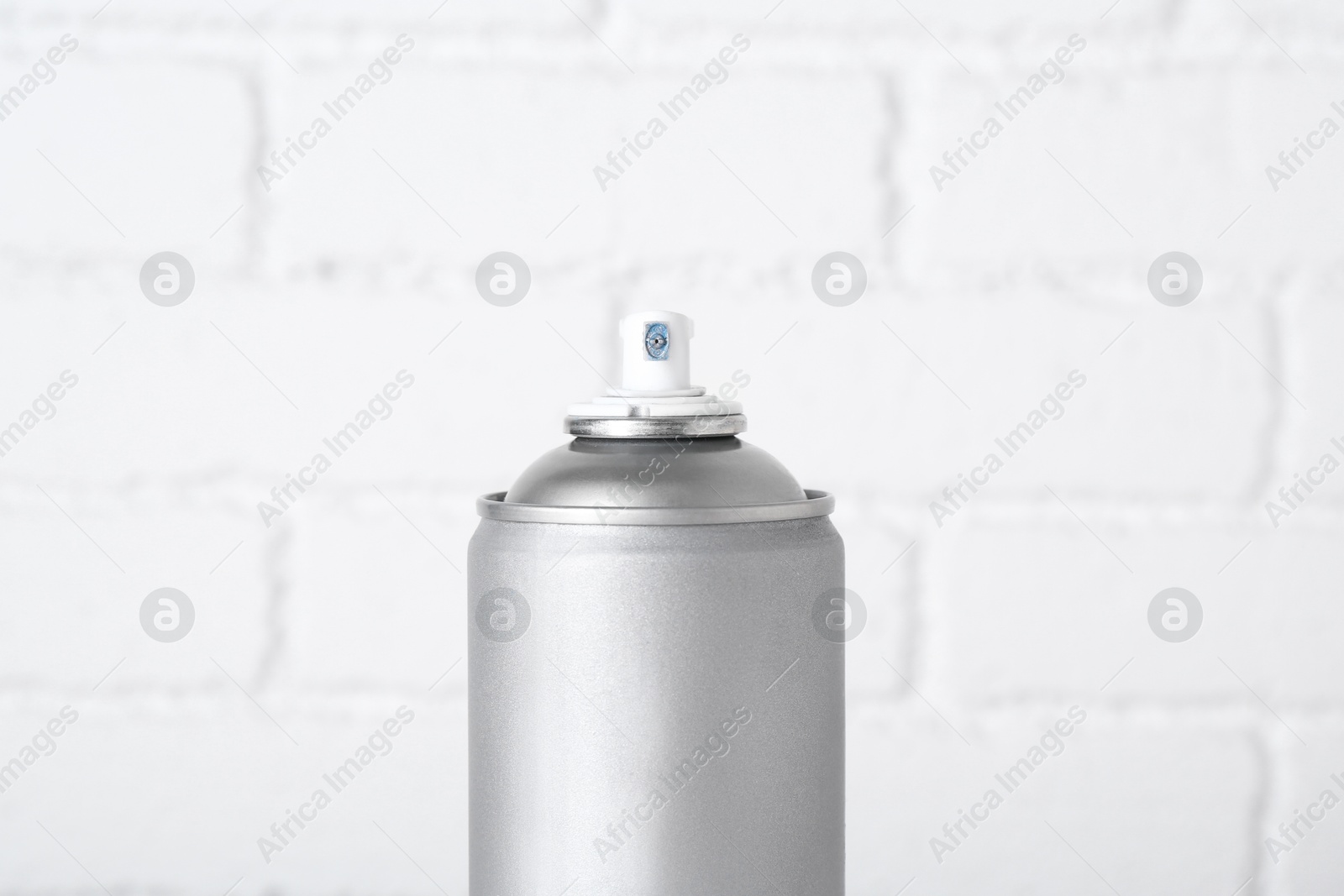 Photo of Can of spray paint near white brick wall, closeup