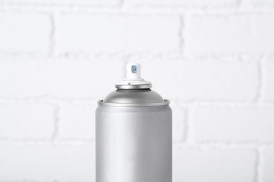 Can of spray paint near white brick wall, closeup