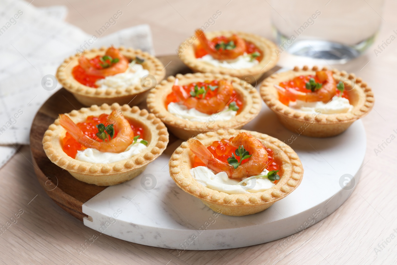 Photo of Delicious canapes with shrimps, red caviar and cream cheese on light table