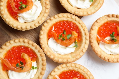 Delicious canapes with shrimps, red caviar and cream cheese on board, flat lay