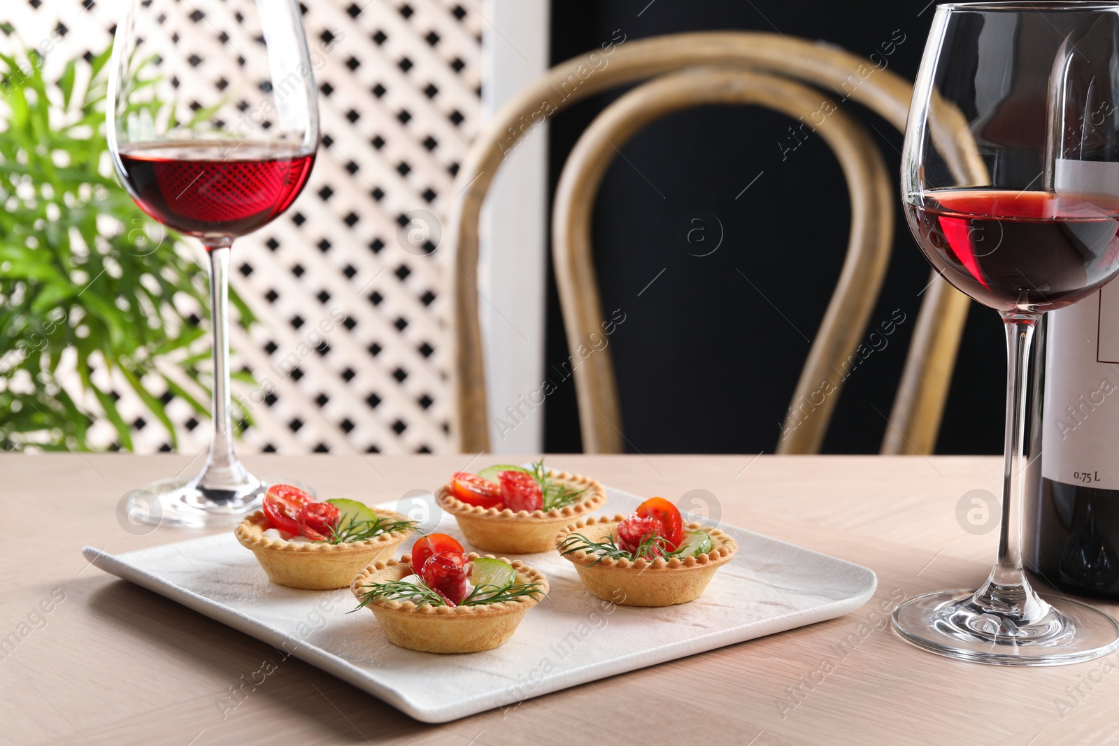 Photo of Delicious canapes with dry smoked sausages, cream cheese and vegetables served on wooden table