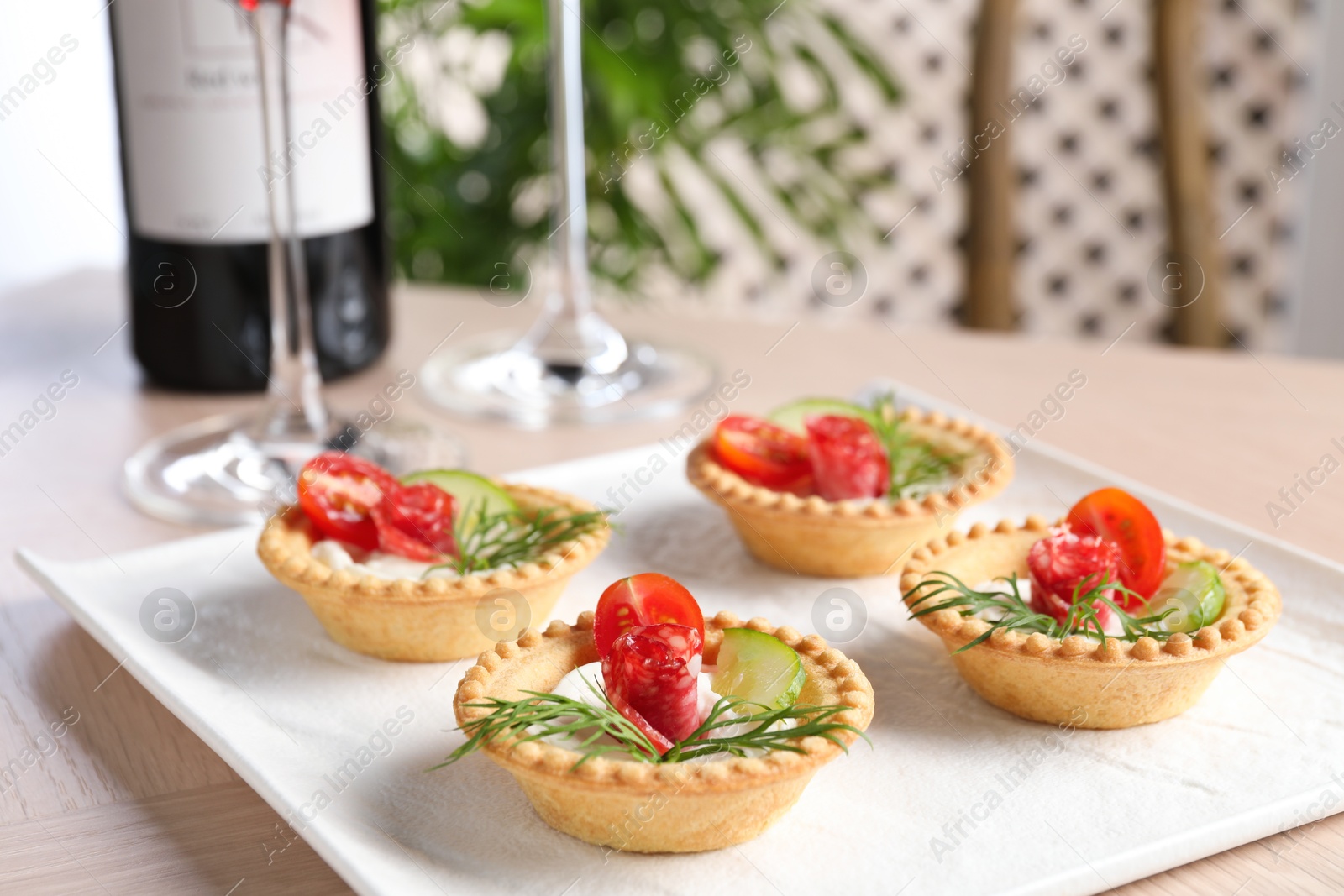 Photo of Delicious canapes with dry smoked sausages, cream cheese and vegetables on wooden table, closeup