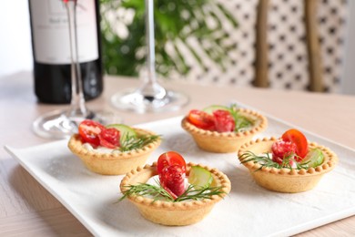 Delicious canapes with dry smoked sausages, cream cheese and vegetables on wooden table, closeup