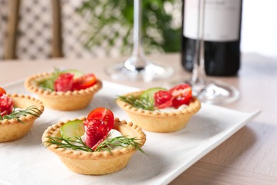 Delicious canapes with dry smoked sausages, cream cheese and vegetables on wooden table, closeup