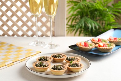 Photo of Delicious canapes with pate and capers served on white table