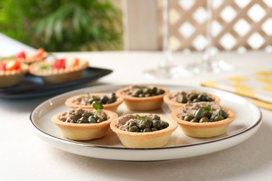 Photo of Delicious canapes with pate and capers on white table