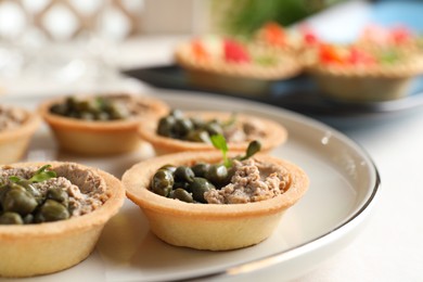 Photo of Delicious canapes with pate and capers on white table, closeup