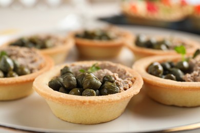 Delicious canapes with pate and capers on table, closeup