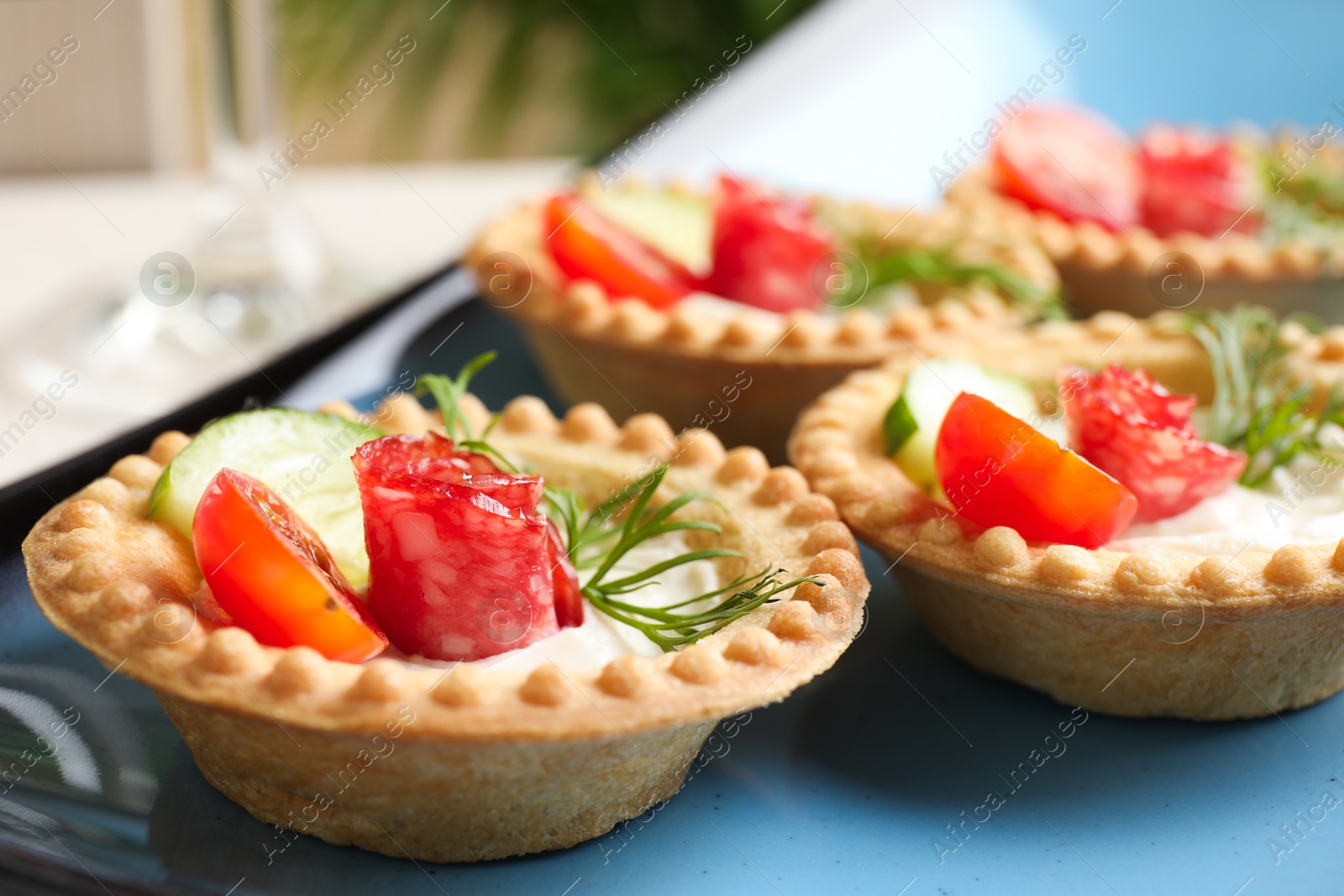 Photo of Delicious canapes with dry smoked sausages, cream cheese and vegetables on table, closeup