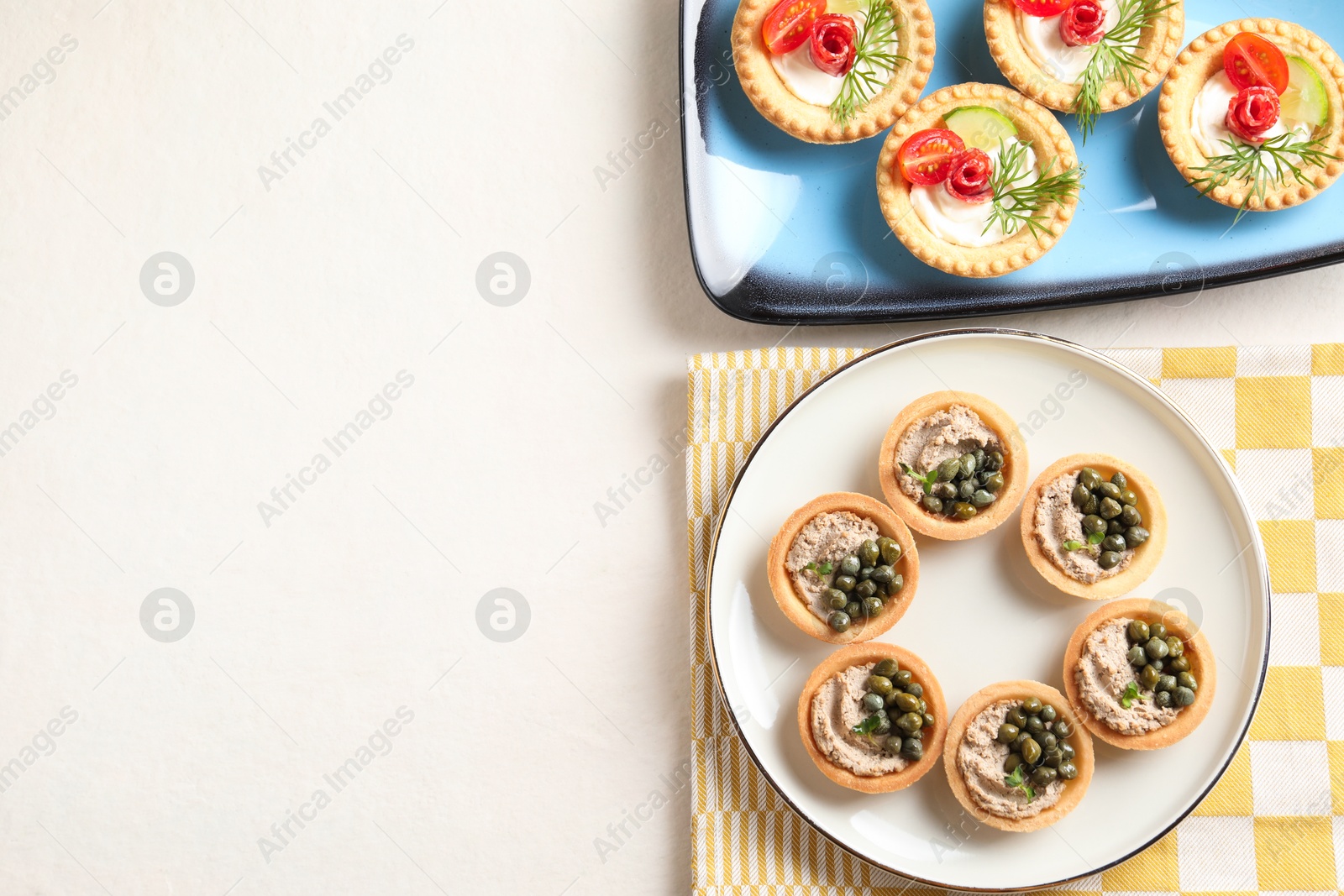 Photo of Delicious canapes with pate, dry smoked sausages and capers on light table, flat lay. Space for text