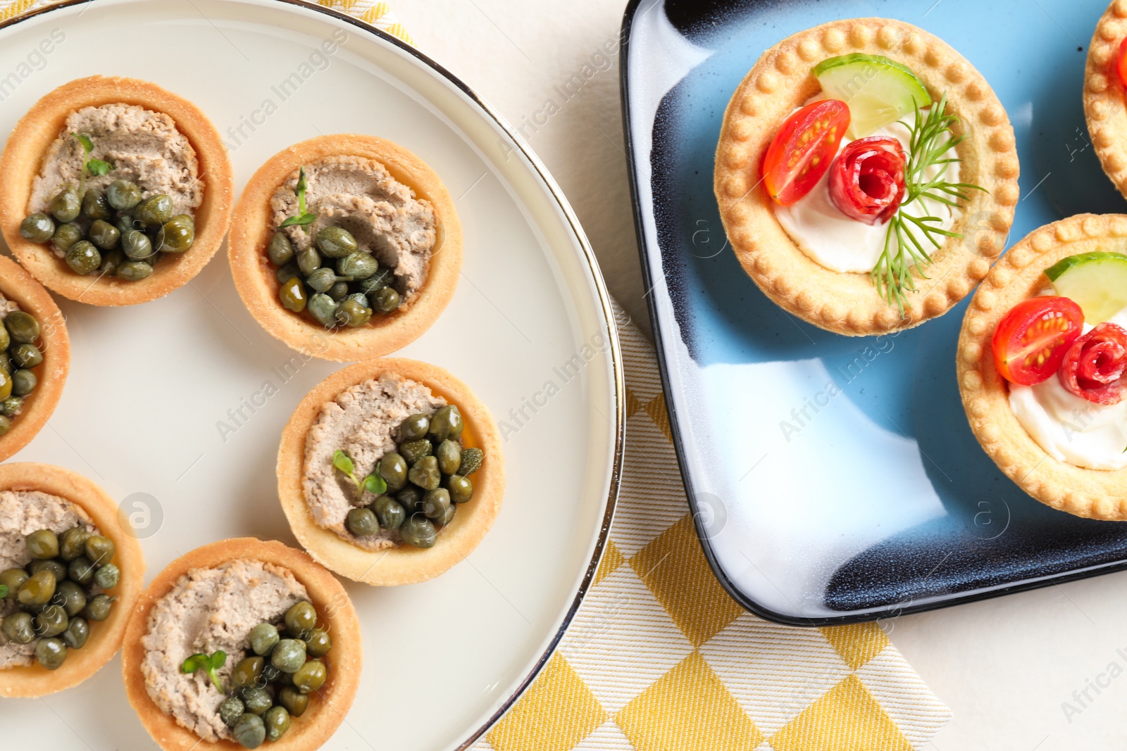 Photo of Delicious canapes with pate, dry smoked sausages and capers on light table, flat lay