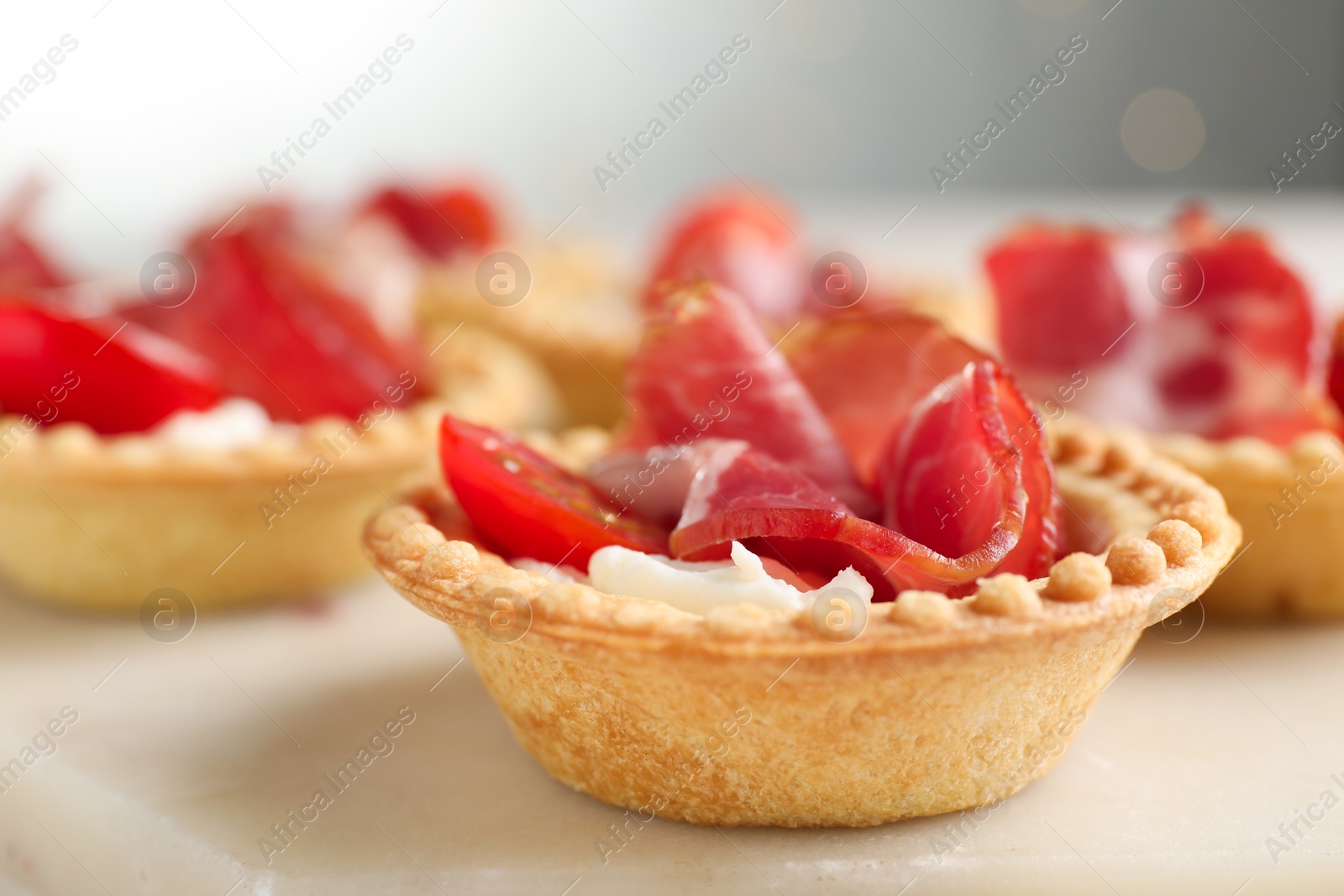 Photo of Delicious canapes with jamon, cream cheese and cherry tomatoes on table, closeup