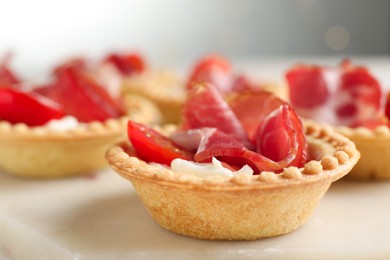 Photo of Delicious canapes with jamon, cream cheese and cherry tomatoes on table, closeup