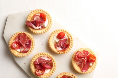 Photo of Delicious canapes with jamon, cream cheese and cherry tomatoes on white table, top view