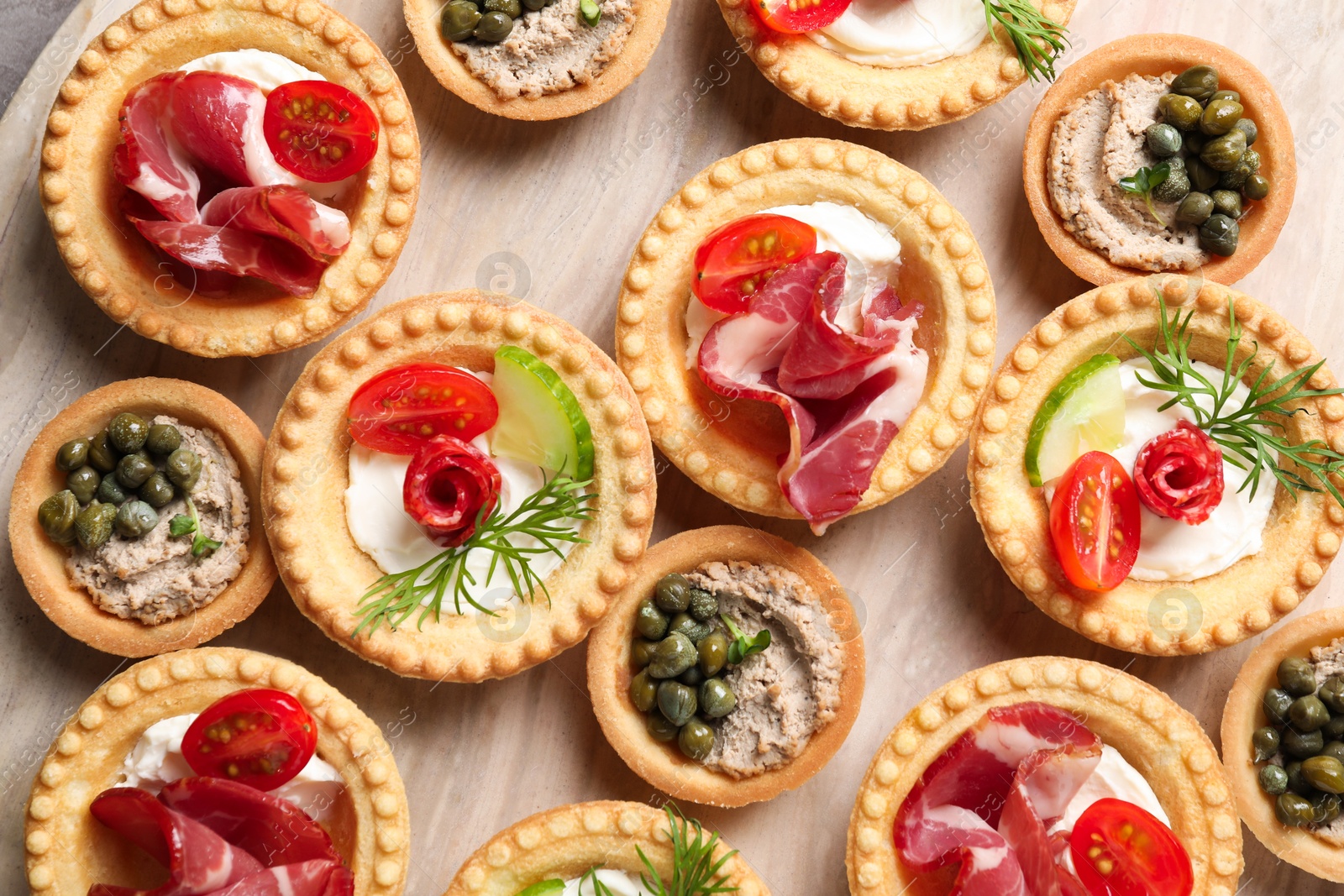 Photo of Delicious canapes with jamon, pate and dry smoked sausages on table, flat lay