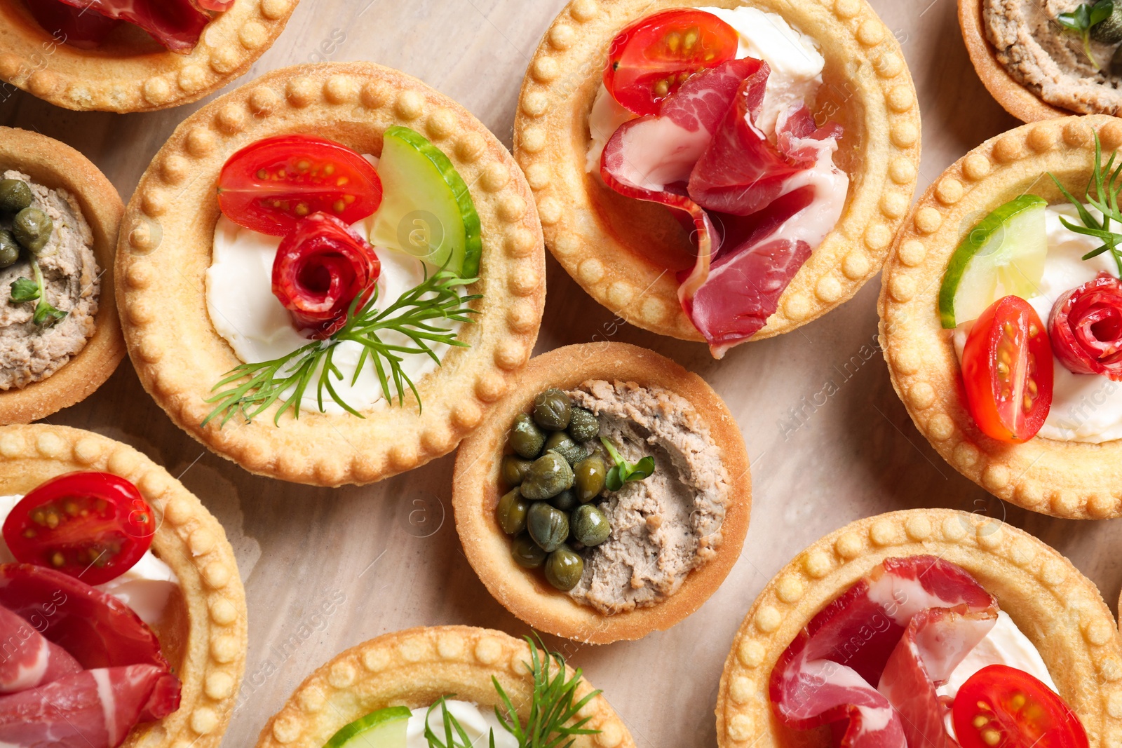 Photo of Delicious canapes with jamon, pate and dry smoked sausages on table, flat lay