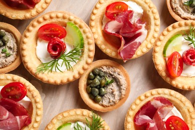 Delicious canapes with jamon, pate and dry smoked sausages on table, flat lay