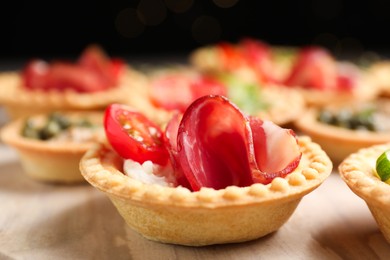 Delicious canapes with jamon, cream cheese and tomato on table, closeup