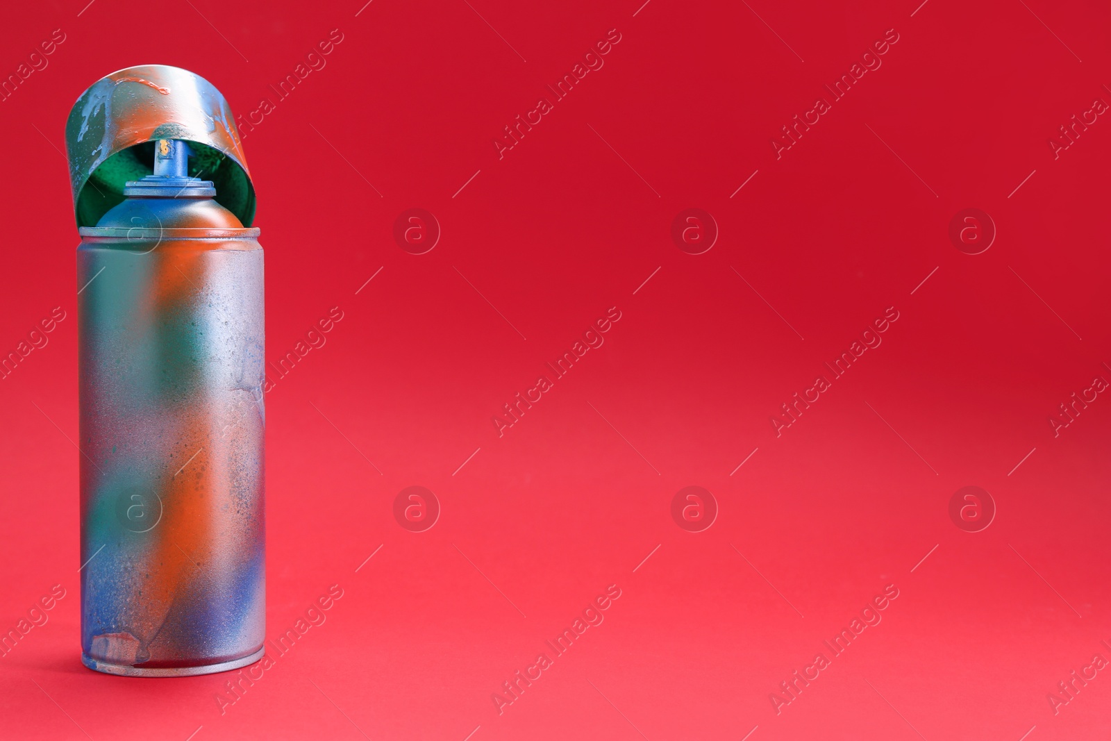 Photo of One can of bright spray paint with cap on red background, space for text